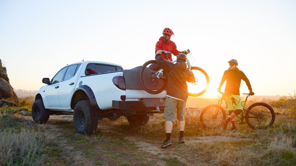 tre amici scaricano bicicletta dal furgone al tramonto nella natura
