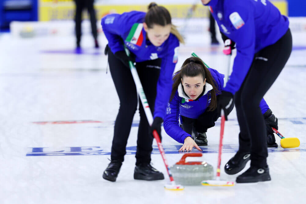 Atlete di Curling che fanno scivolare la pietra di granito